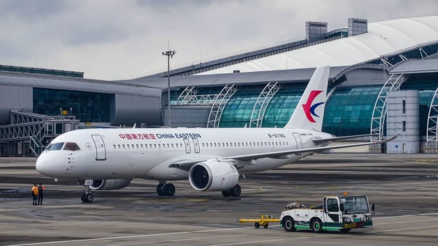 China Eastern Airlines Airbus parked at a modern airport terminal on a cloudy day, ready for departure.