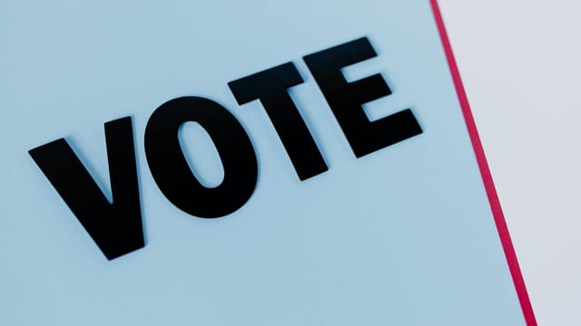 Close-up of the word 'VOTE' on a minimal background, emphasizing voting importance.