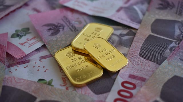 Close-up of gold bars on Thai baht banknotes, symbolizing wealth and prosperity.