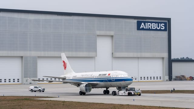 Air China aircraft being towed in front of Airbus hangar.