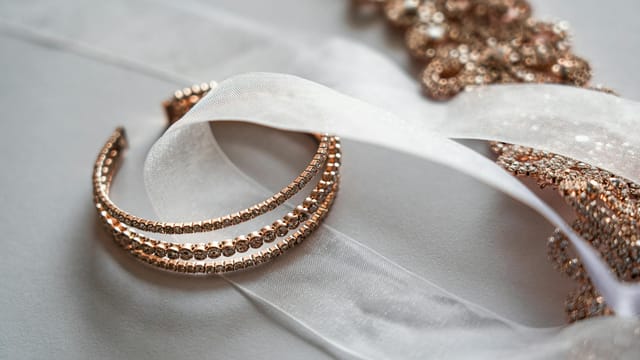 Close-up of luxurious rose gold jewelry on a sheer satin fabric, perfect for bridal occasions.