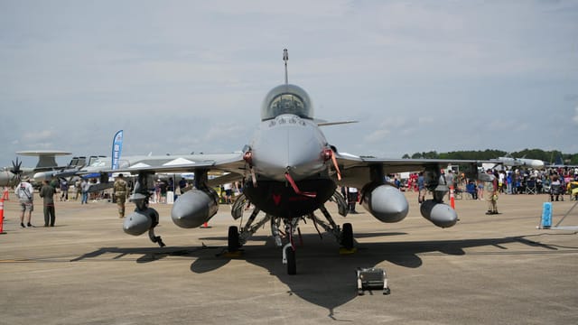 A fighter jet showcased at an airshow in Hampton, Virginia with spectators in the background.