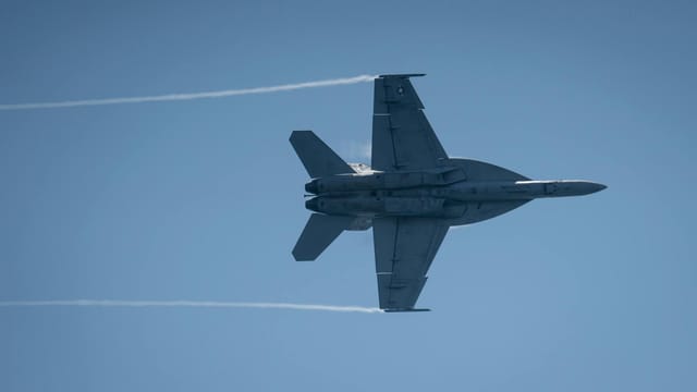 F/A-18 Super Hornet jet flying at high speed during an airshow with clear skies.