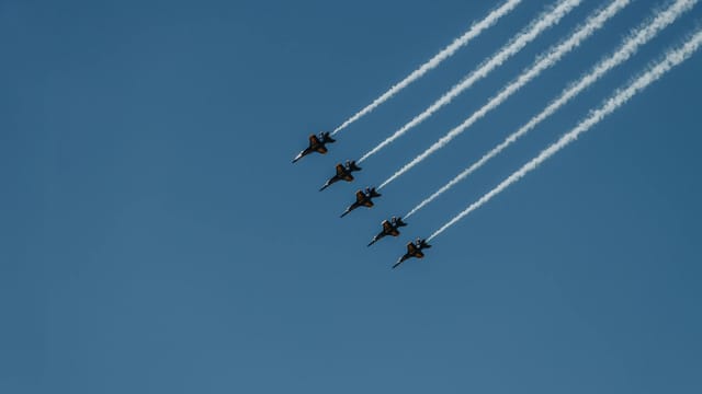 Navy's Blue Angels performing aerial stunts in a clear sky.