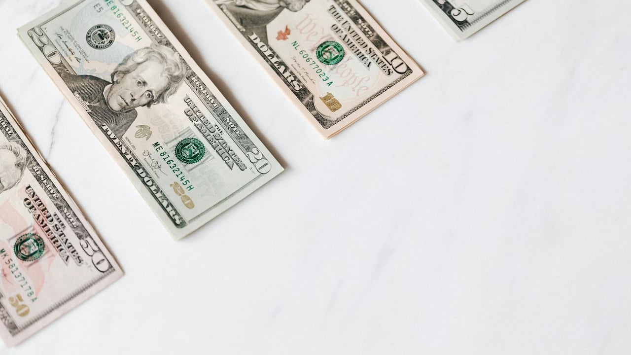 US dollar banknotes arranged on a clean white surface, showcasing different denominations.