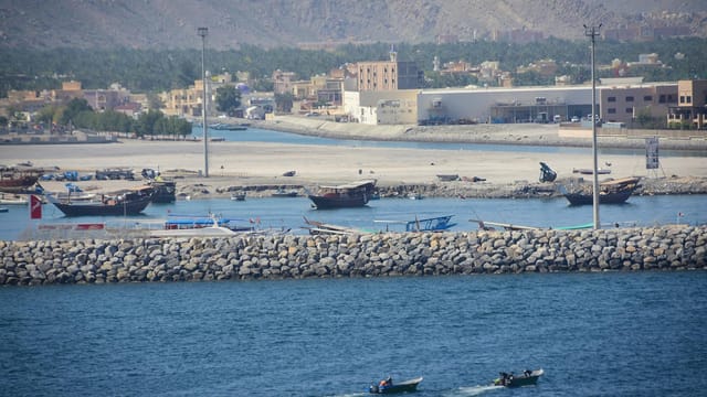 A vibrant harbor scene at al-Chasab Musandam with boats and mountains in the background.