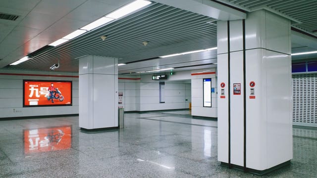 A spacious and modern metro station interior with an advertising board and reflective flooring, captured in high-quality detail.