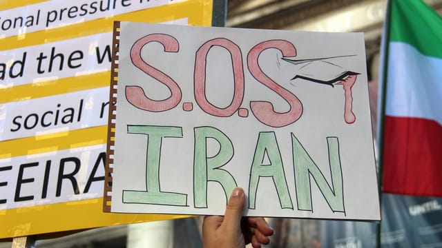 Protest sign reading SOS Iran during a demonstration in Vancouver, raising awareness for Iranian issues.