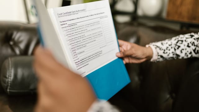 Close-up of a person examining a credit card authorization form inside an office setting.