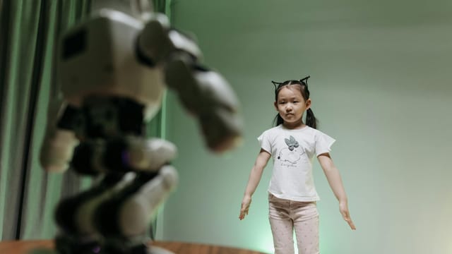 An Asian child interacts with a humanoid robot indoors, embracing innovation and play.