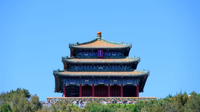 Beautiful view of a traditional Chinese pagoda amidst lush greenery under a bright blue sky.