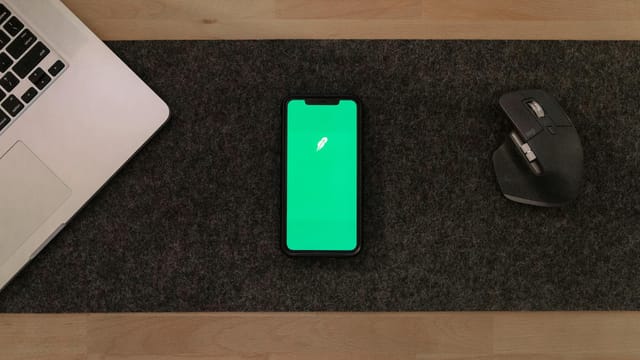 Modern workspace with smartphone, laptop, and mouse on wooden desk.