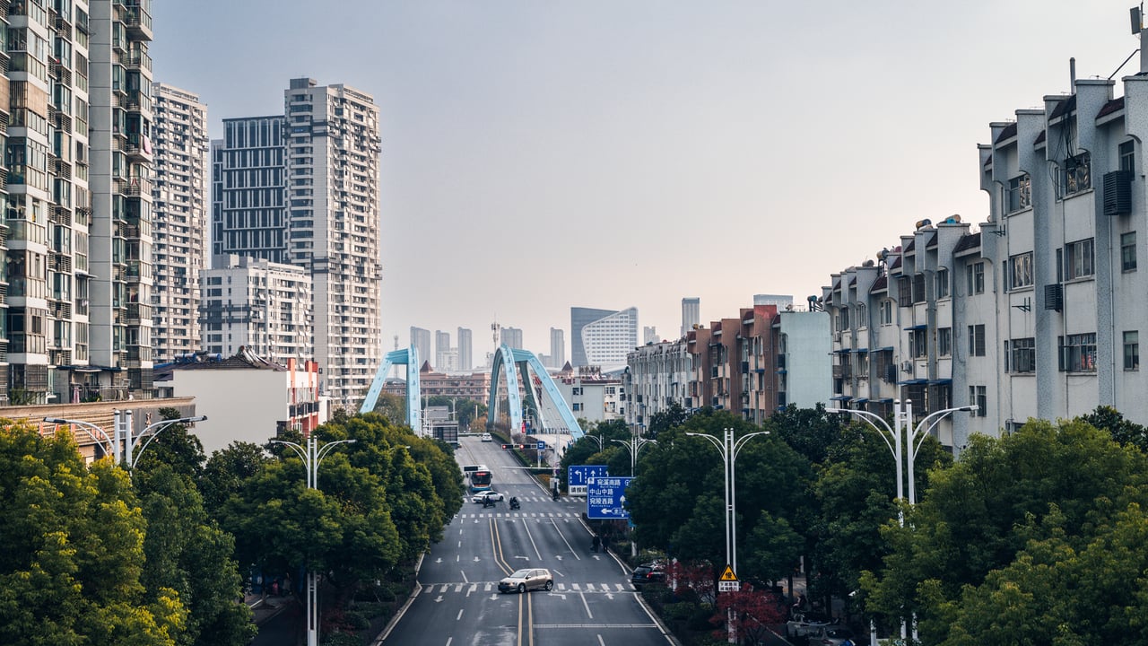 A vibrant city scene in Xuancheng, Anhui, featuring a prominent blue bridge amidst tall buildings.