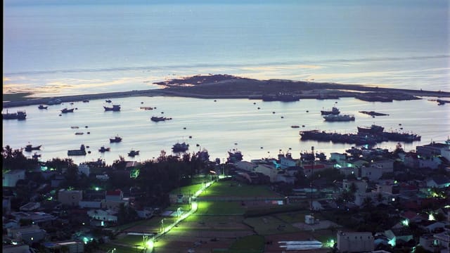 Serene aerial view of Quang Ngai coastline and boat-filled harbor at twilight, Vietnam.