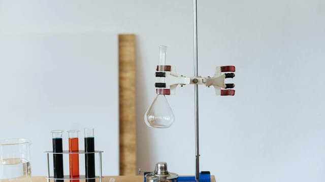 Chemical test with empty flask mounted on ring stand while burner under flask and tubes filled with reagents in modern lab