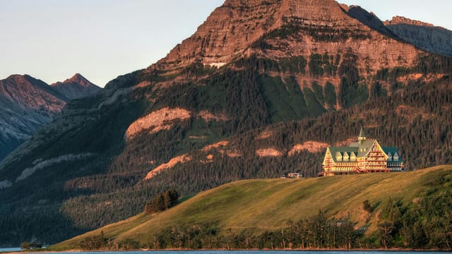A captivating view of Prince of Wales Hotel with mountains and lake in Waterton Park, Canada.
