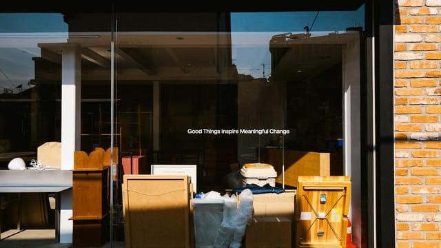 A storefront window featuring the quote 'Good Things Inspire Meaningful Change' with furniture and decorations inside.