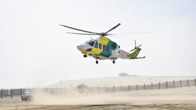 A medical helicopter hovers above the sandy desert in Doha, Qatar, ready for urgent transport.