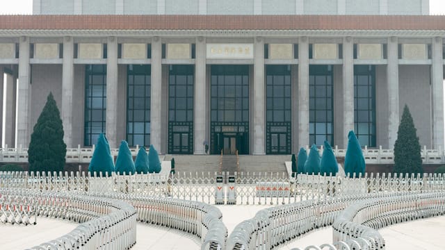 View of the historic building with grand columns and security barriers in an urban setting.
