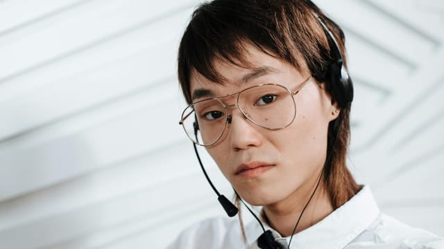 Close-up of a call center agent with eyeglasses and headset, indoors.