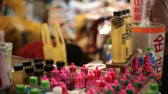 Vibrant display of colorful bottles at an Asian street market, offering diverse products.
