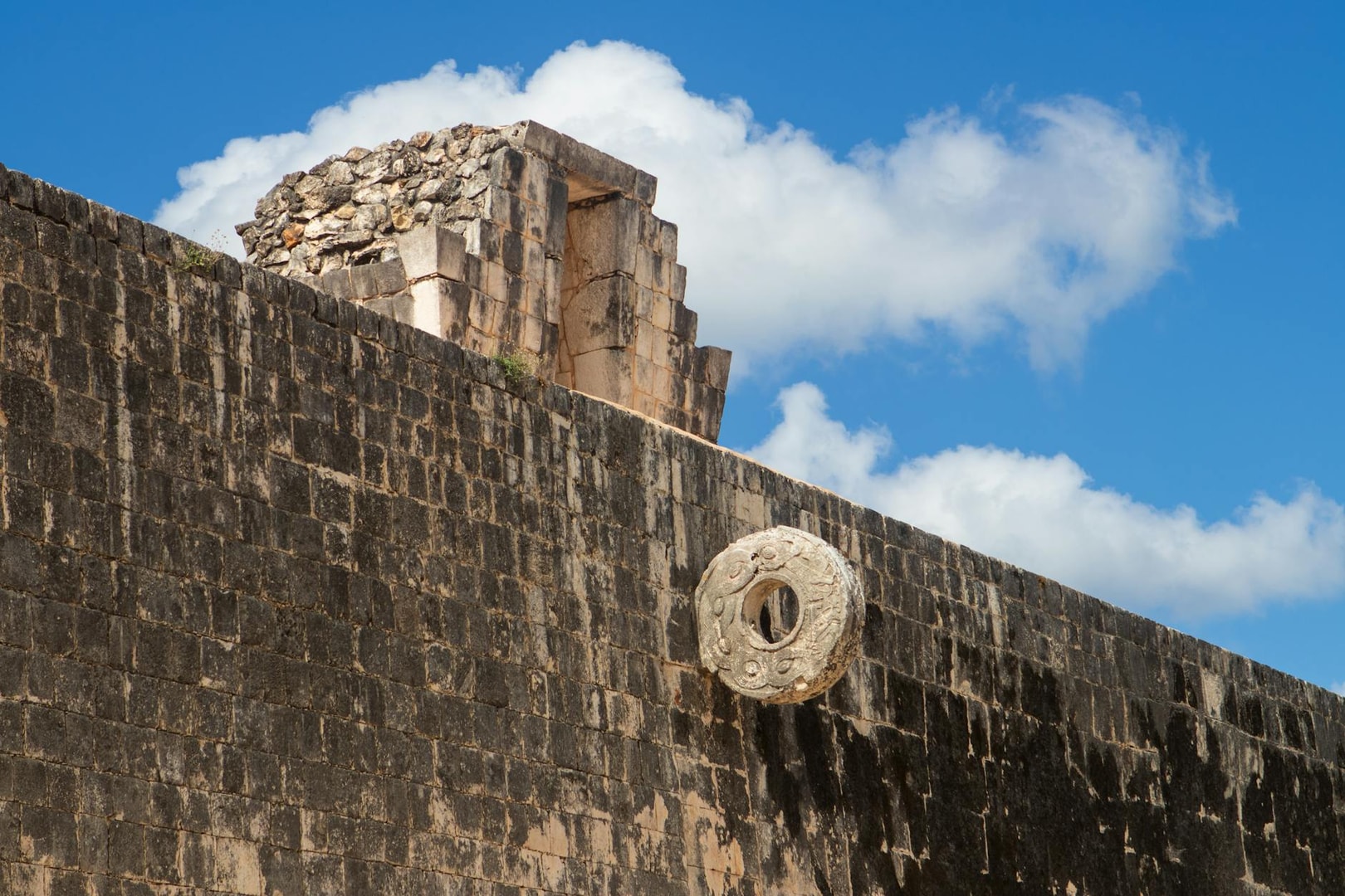 Explore the ancient Mayan ballcourt at Chichen Itza under a vibrant blue sky.