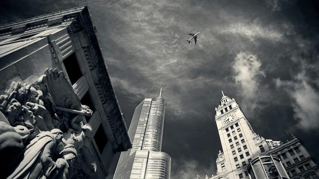 A monochrome view of Chicago skyscrapers with a plane overhead, capturing architectural elegance.