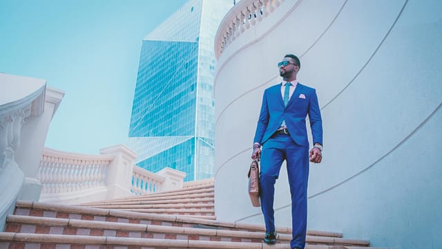 Stylish businessman walking up stairs with skyscraper backdrop in the UAE.