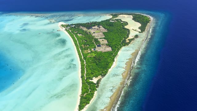 A breathtaking aerial view of a lush tropical island surrounded by turquoise waters.