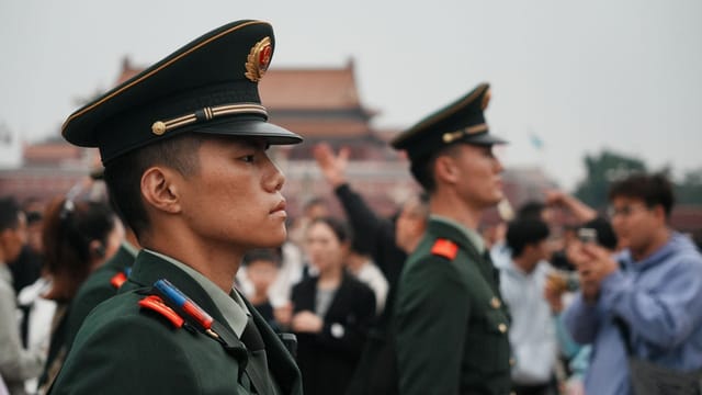 Uniformed guards stand vigil amidst a crowd at Tiananmen Square.