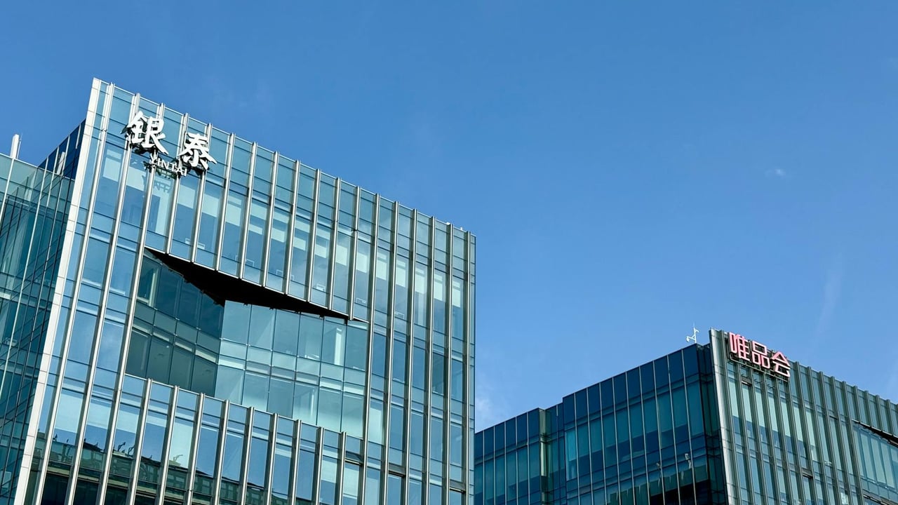 Close-up of modern glass facade buildings under a clear blue sky in Shanghai, China.