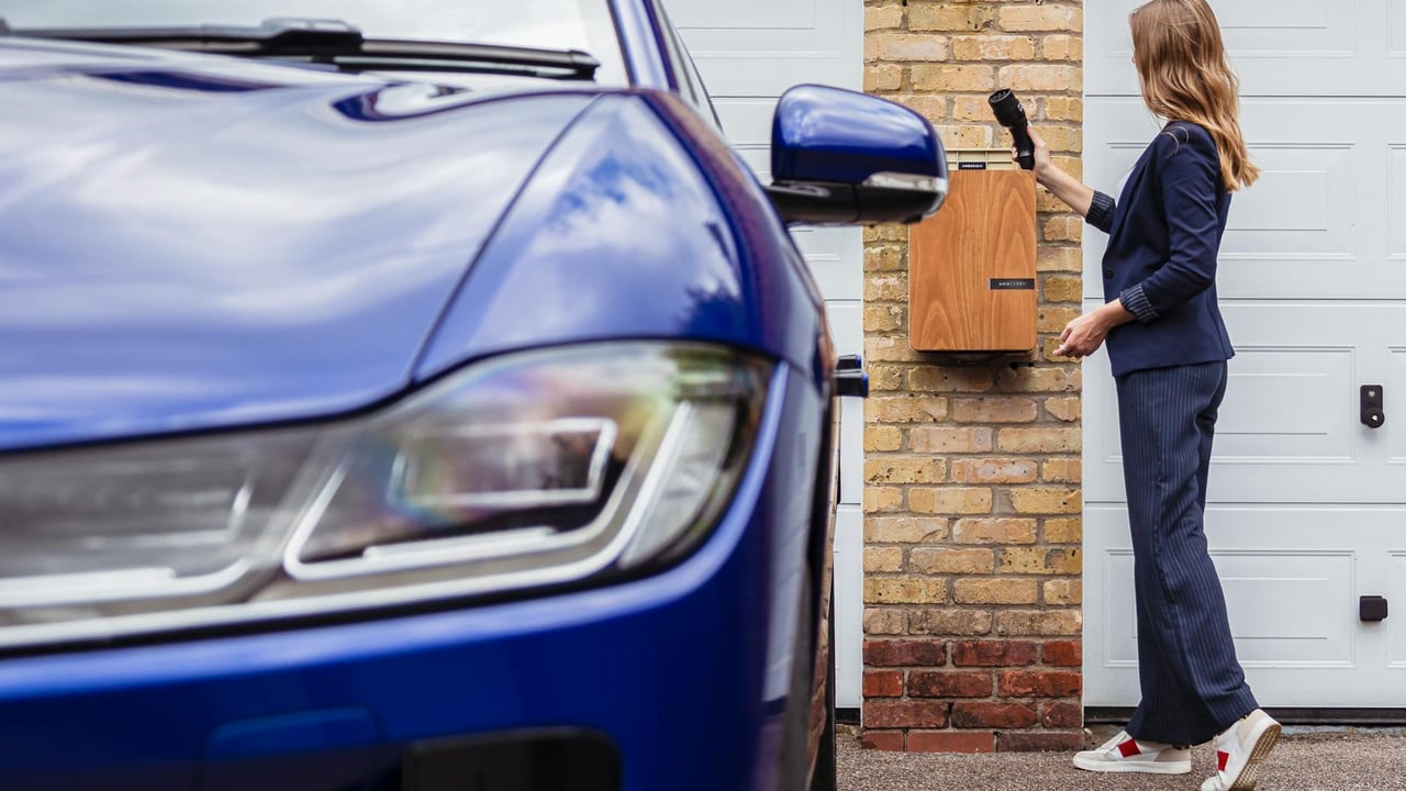 Woman charging an electric car at a home station, promoting sustainability.