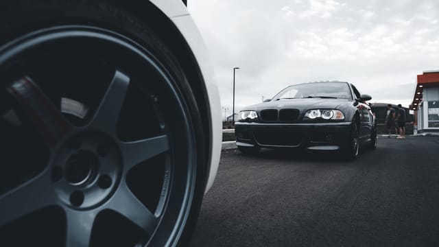 Dynamic shot of sleek sports cars on a wide asphalt road emphasizing power and speed.