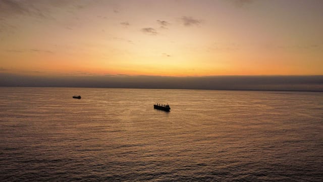 Aerial view of ships sailing on the Pacific Ocean during a beautiful sunset near Antofagasta, Chile.