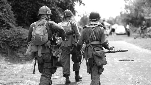 Group of soldiers in period uniforms during a historical military reenactment outdoors.