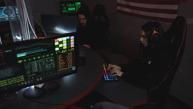 Cybersecurity professionals working on computer systems, focusing on data protection in a dimly lit room.