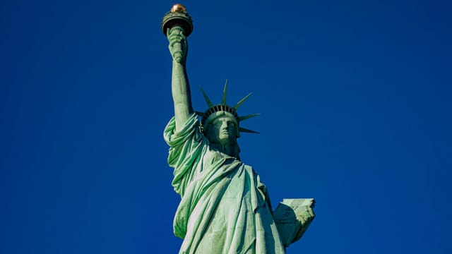 Iconic Statue of Liberty with a majestic blue sky backdrop, symbol of freedom in New York City.