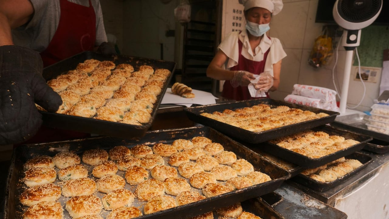 Two bakers preparing fresh sesame pastries in a traditional bakery in Taizhou, Zhejiang, China.