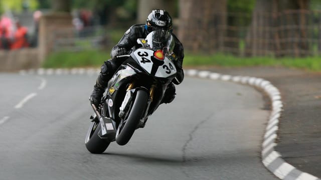 Dynamic shot of a motorcyclist speeding through the Isle of Man TT course.