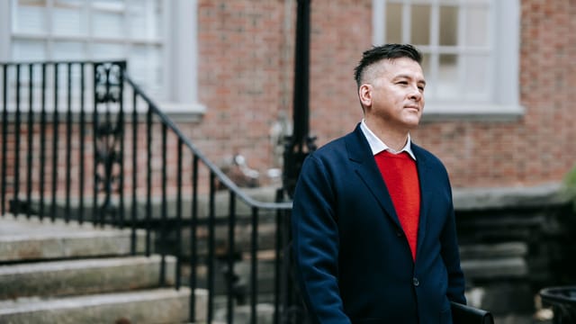 A confident man in professional attire stands outdoors, exuding style and poise.