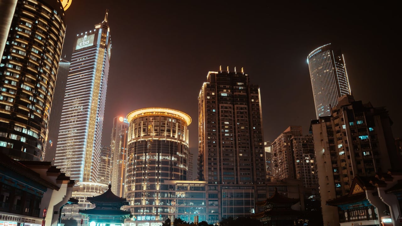 Vibrant city skyline at night with illuminated skyscrapers and modern architecture.