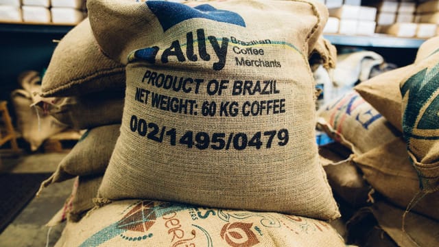 Stack of Brazilian coffee bags in a warehouse, highlighting global trade and commerce.
