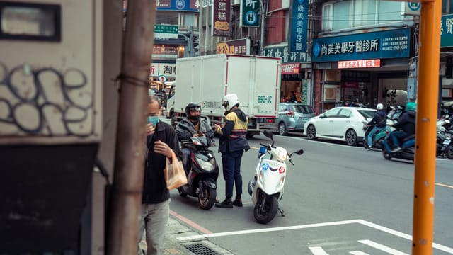 Urban street scene featuring a police officer interacting with a motorcyclist, capturing city life.