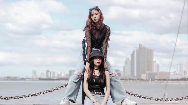 Two stylish young women posing by the waterfront with Manila skyline in the background.