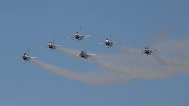 US Air Force Thunderbirds fly in formation against a clear blue sky during an air show.