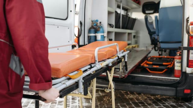 A paramedic loads a stretcher into an ambulance, showcasing emergency medical services in action.