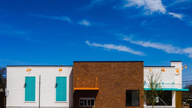 Front view of a modern fast food restaurant with brick facade and clear blue sky.