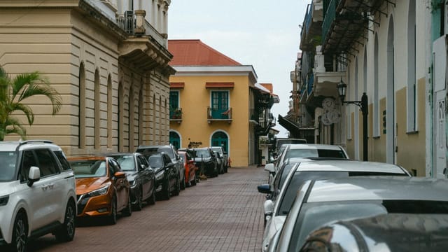 Charming street in Panama City with parked cars and colonial architecture under a clear sky.
