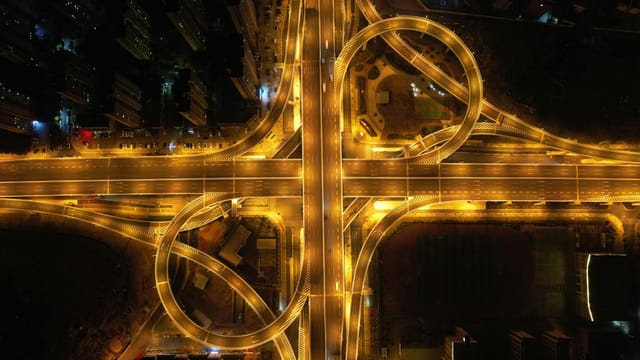 A stunning aerial view of a brightly lit highway interchange in China at nighttime, showcasing intricate patterns.