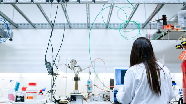 A female scientist conducting research in a contemporary laboratory full of equipment.
